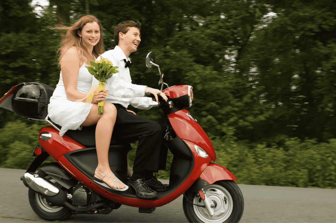 a couple who have just been married on a red bike