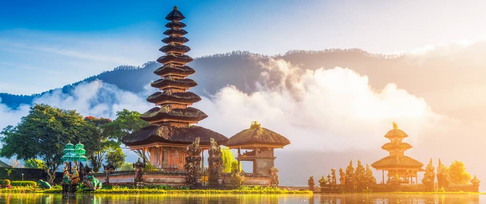 scenic view of a bali temple with mountains and clouds in the background