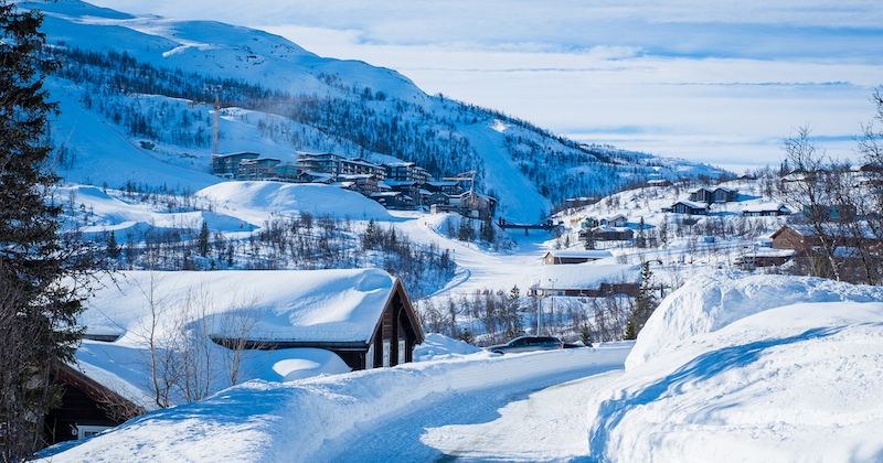 Traditional wooden ski chalets on a snowy hillside with pine forest, Trysil, Norway.